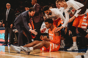Elijah Hughes slides on the floor by the Syracuse bench.