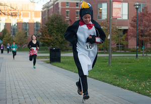 Junior Vivian Gomez runs in the Halloween Fun Run/ Walk dressed in a penguin suit. 