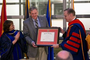 College of Arts and Sciences Dean Karin Ruhlandt and Chancellor Kent Syverud present the degree of World War II veteran and Medal of Honor recipient Forrest Lee Vosler to his son, Steve.