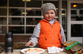 Rylan Renski enjoys a snack before the game on Waverly Ave. during a tailgate.