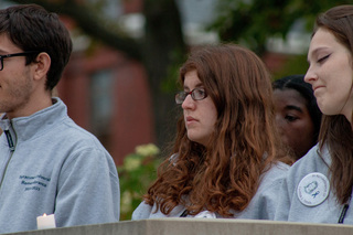 Remembrance Scholars Emily Steinberger, Ronald Ditchek and Jenna Merry stand in silence before an electric candle. Closing remarks are made by scholar Mira Berenbaum as all of the scholars took their place behind the Remembrance Wall. 