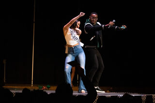 Dumervil and Honna Santos Lopez, a contestant representing the Dominican Republic, greet each other with a hip bump as she is introduced to the crowd. Dumervil welcomed each contestant to the stage with a different performative gesture. 